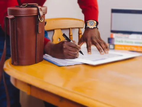 Mains qui remplissent un document imprimé au stylo, sur une table en bois