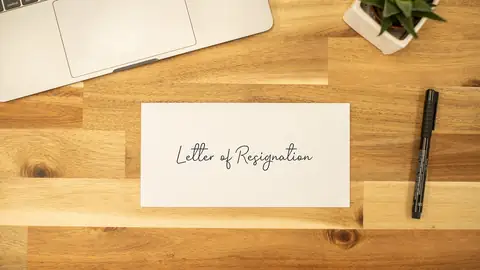 Lettre de démission posée sur un bureau en bois à côté d’un feutre