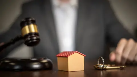 Maquette de maison, clés et marteau de juge sur une table