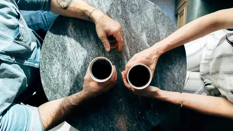 Deux personnes attablées avec une tasse de café, vues d’au-dessus
